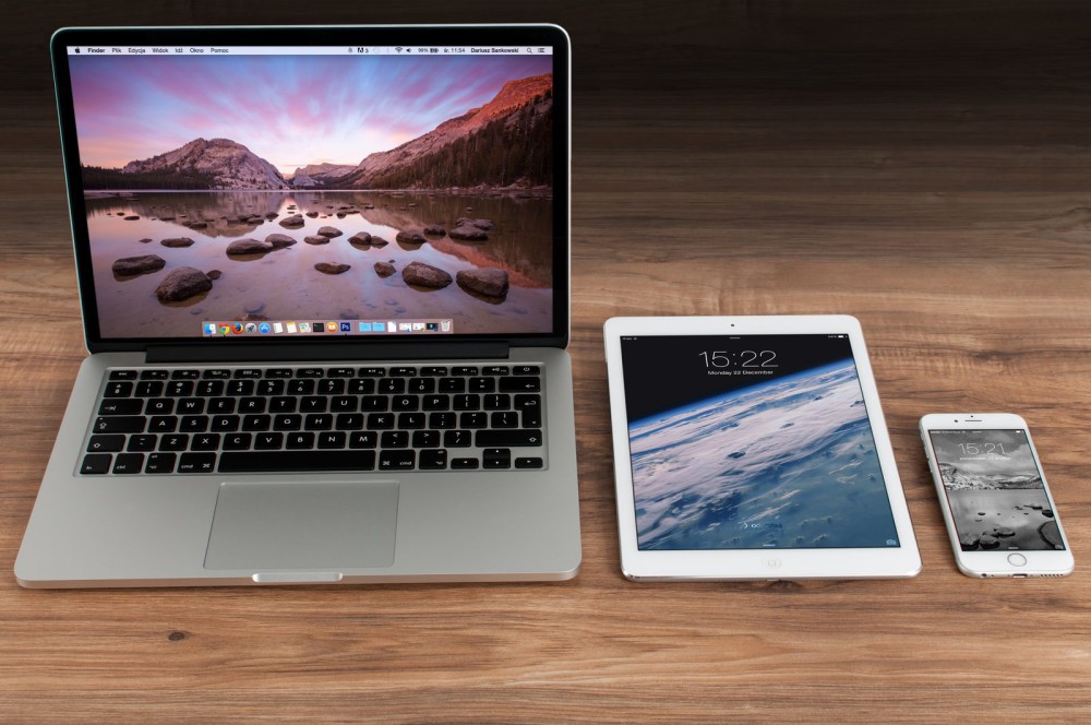 A laptop, tablet and phone side by side on a wooden desk