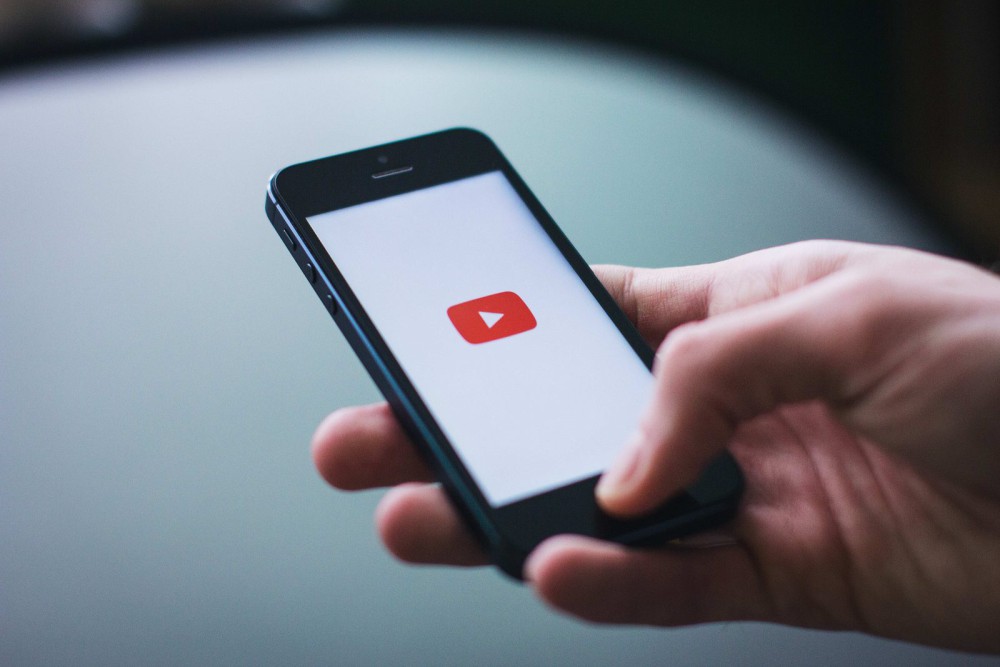 A hand holding a smartphone with a video app open